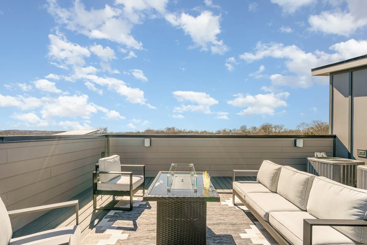 A tranquil rooftop deck at sunset, featuring comfortable outdoor seating and a fire table. The sky glows with evening colors, inviting families to gather, relax, and stargaze after a day of Nashville adventures.