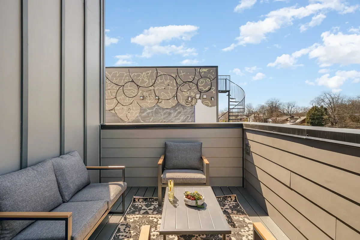 A cozy outdoor seating area with a decorative wall mural and small table set with plants, perfect for intimate gatherings or enjoying a coffee. The scene is relaxed yet artistic, suggesting quiet corners for work or casual networking outdoors.