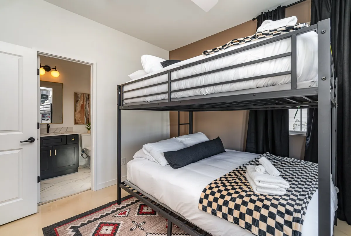 A playful, inviting bedroom with a bunk bed, cheerful rug, and easy access to the bathroom. The decorative towels and thoughtful touches make the space ideal for families or groups with children.